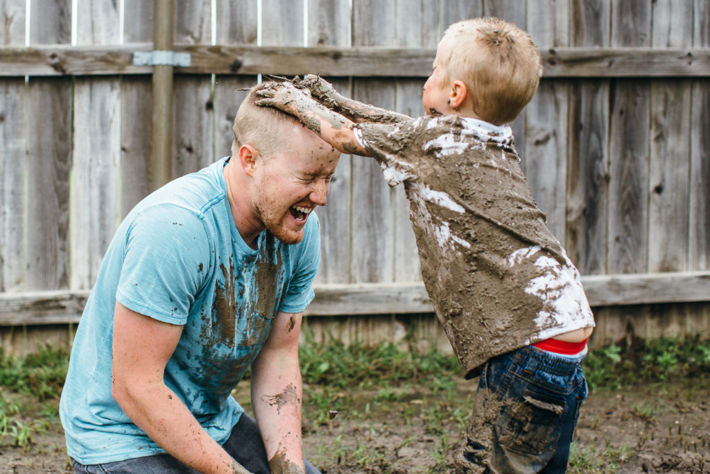 father and son playing in the mud