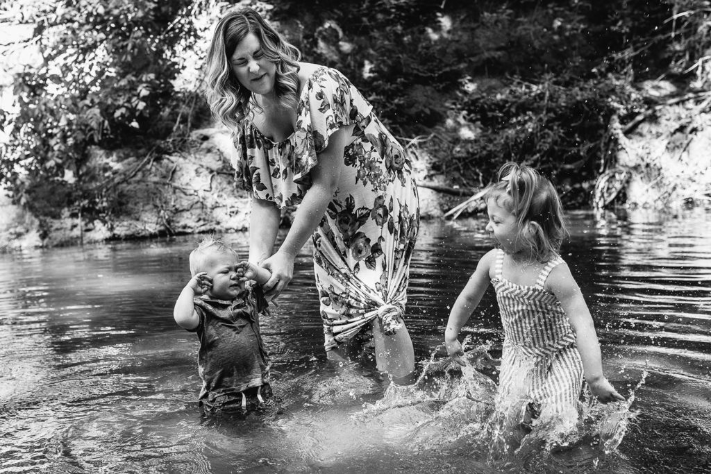 kids splashing in the creek with mommy