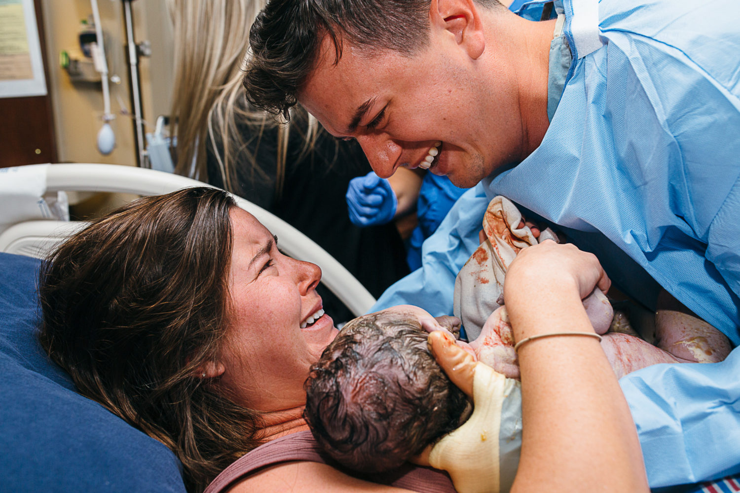 mother and father looking at each other while holding newborn