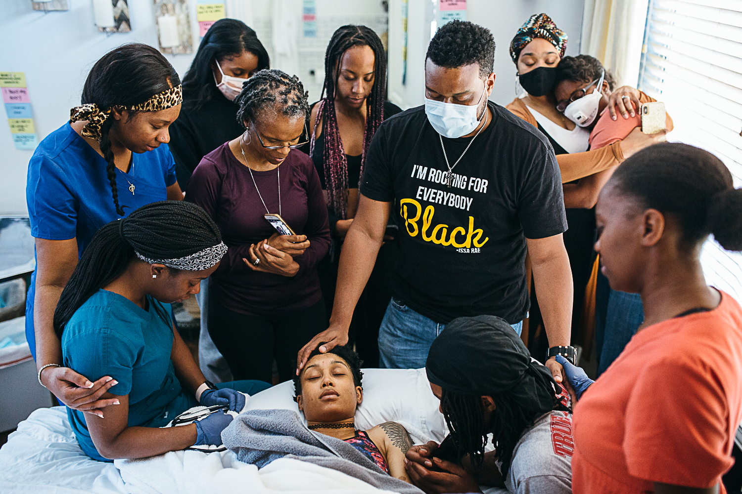 black mother holding her newborn surrounded by her family praying tshirt reads I'm Rooting for Everybody Black