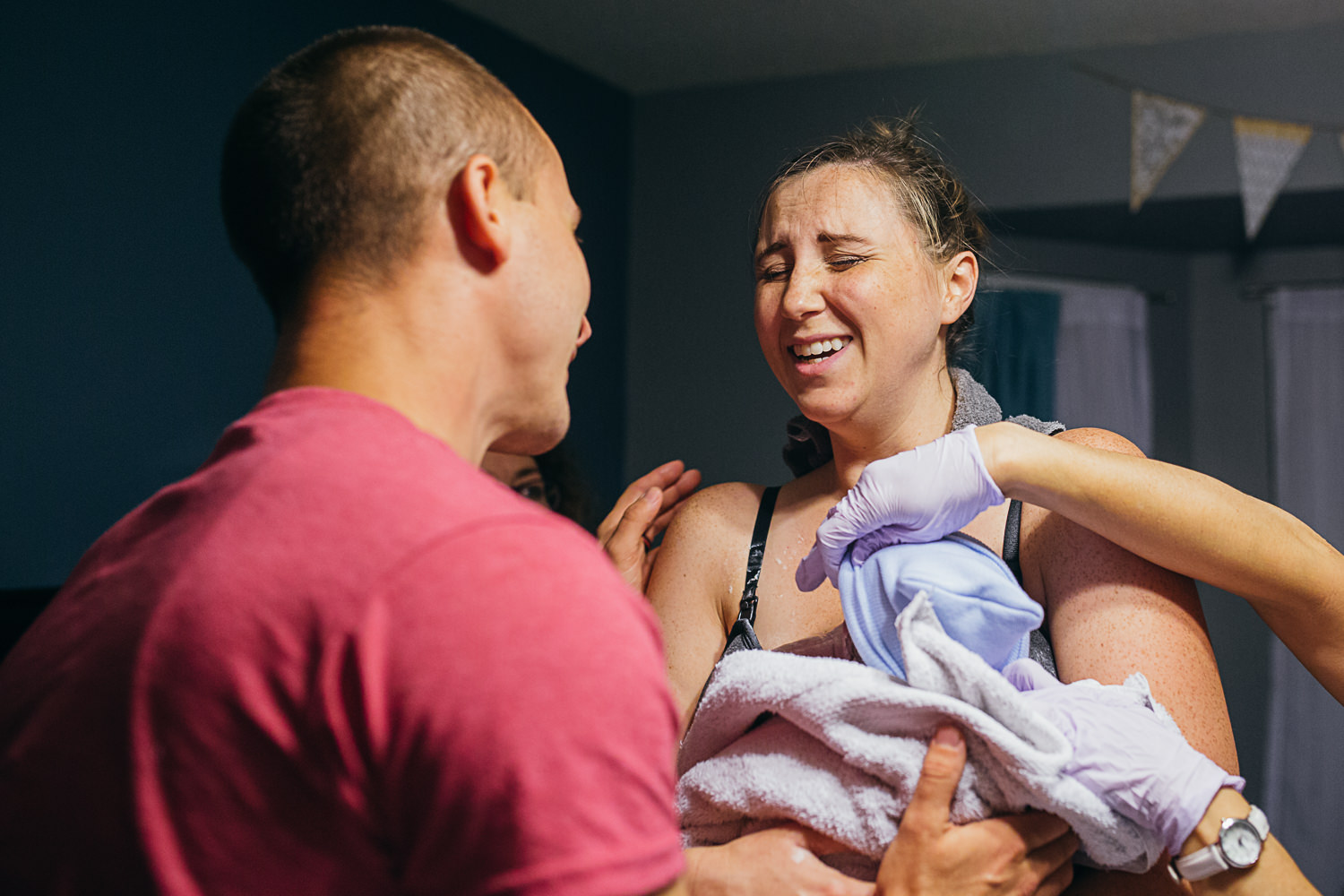 woman who just delivered baby at home looks relieved as her husband stands facing her