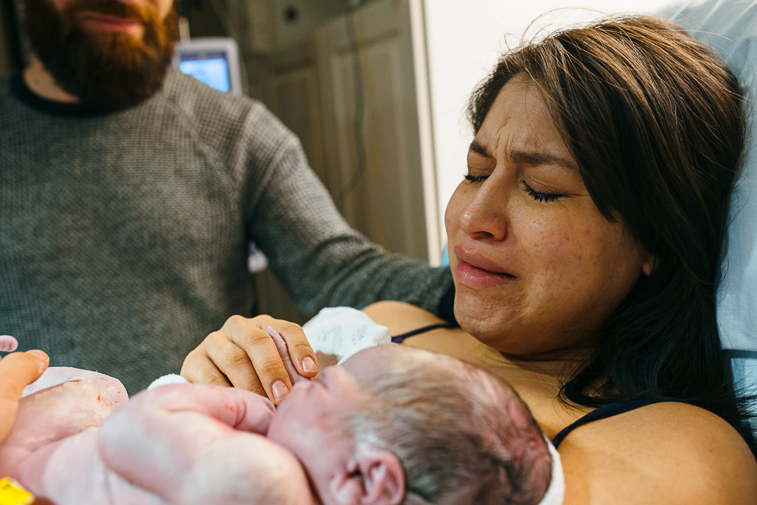 mother cries as she holds her newborn son just moments after he is born