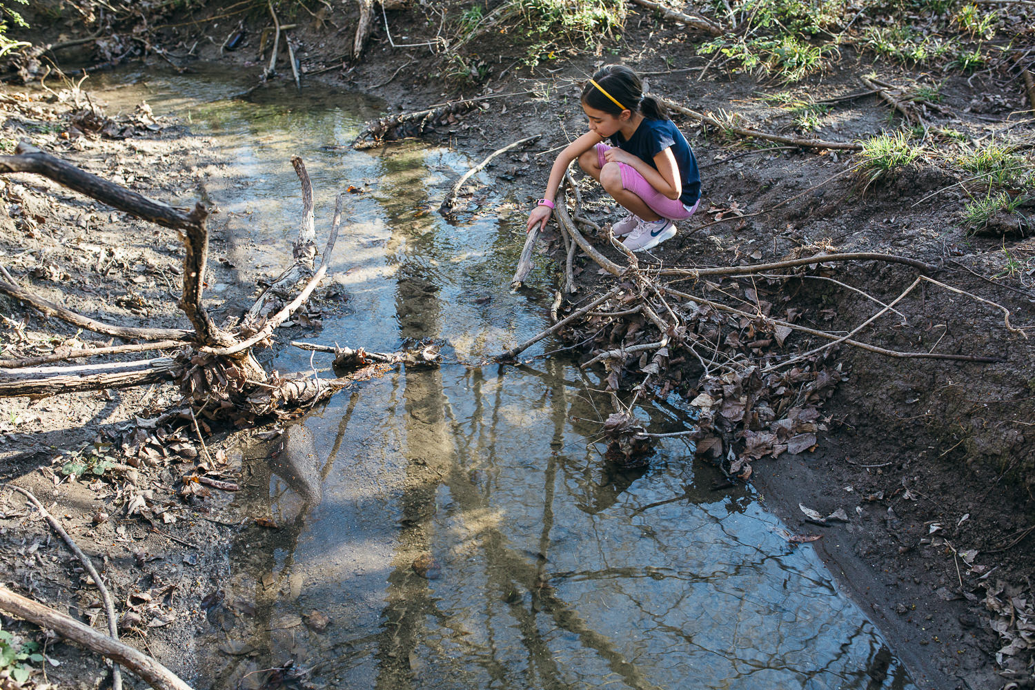 young-girl-playing-on-the-bank-of-a-small-creek