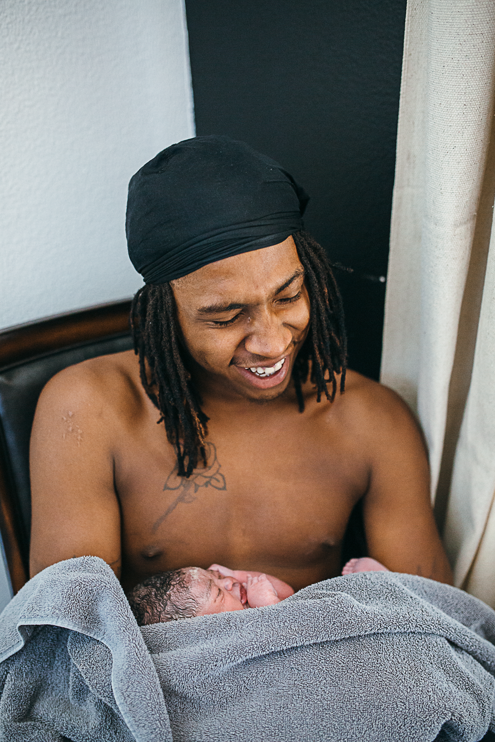 a black father holds his newborn son skin to skin