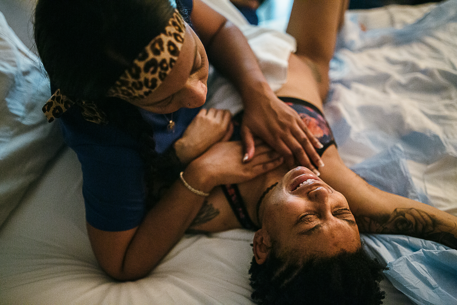 A black laboring mother cries through a contraction as her doula calms her with a hand on her chest