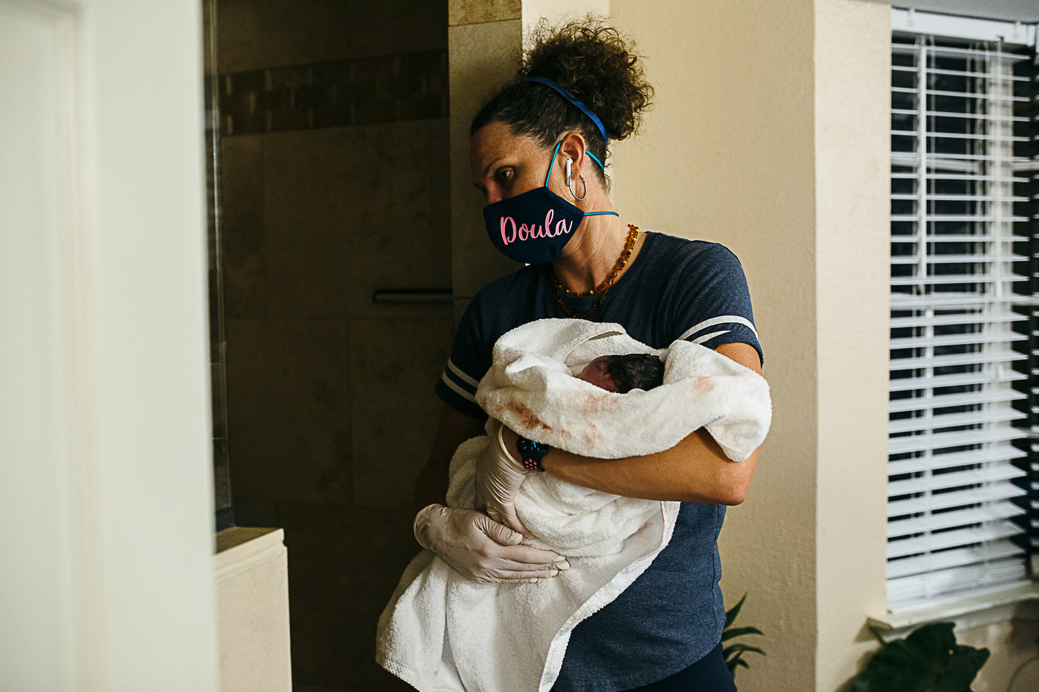 doula holds the baby while mom takes a quick minute to rinse off