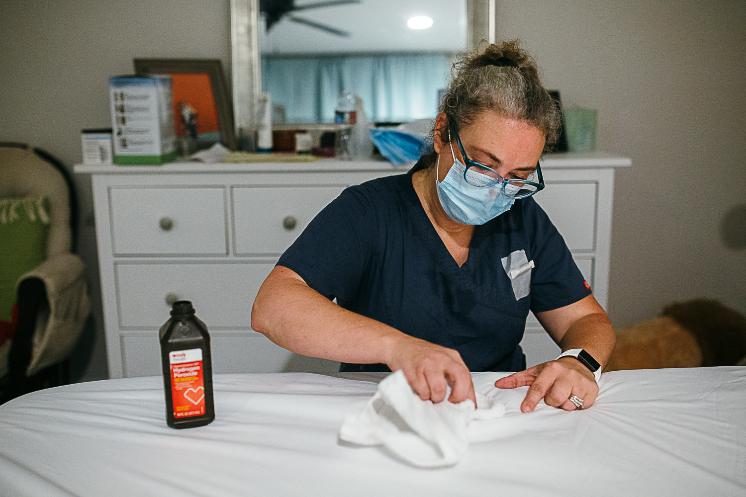 a midwife cleans blood off of the bed sheets