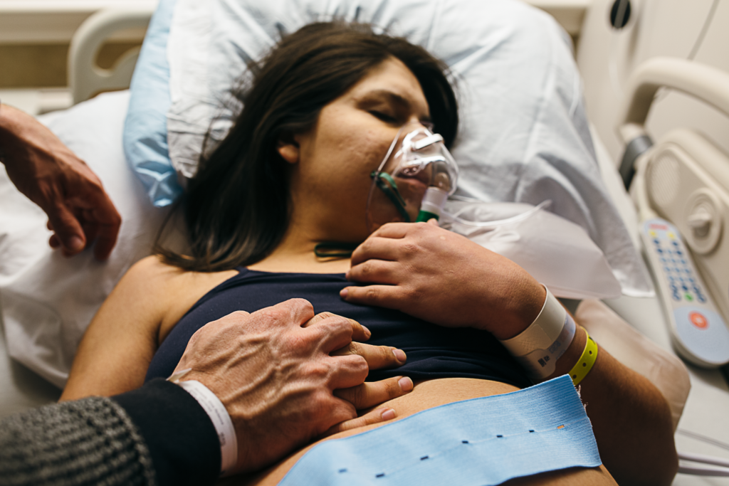 woman holding hands wearing an oxygen mask in labor